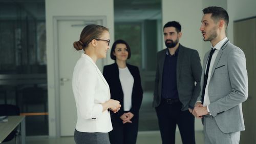 Free Group of professionals in formal attire having a discussion in a modern office setting. Stock Photo
