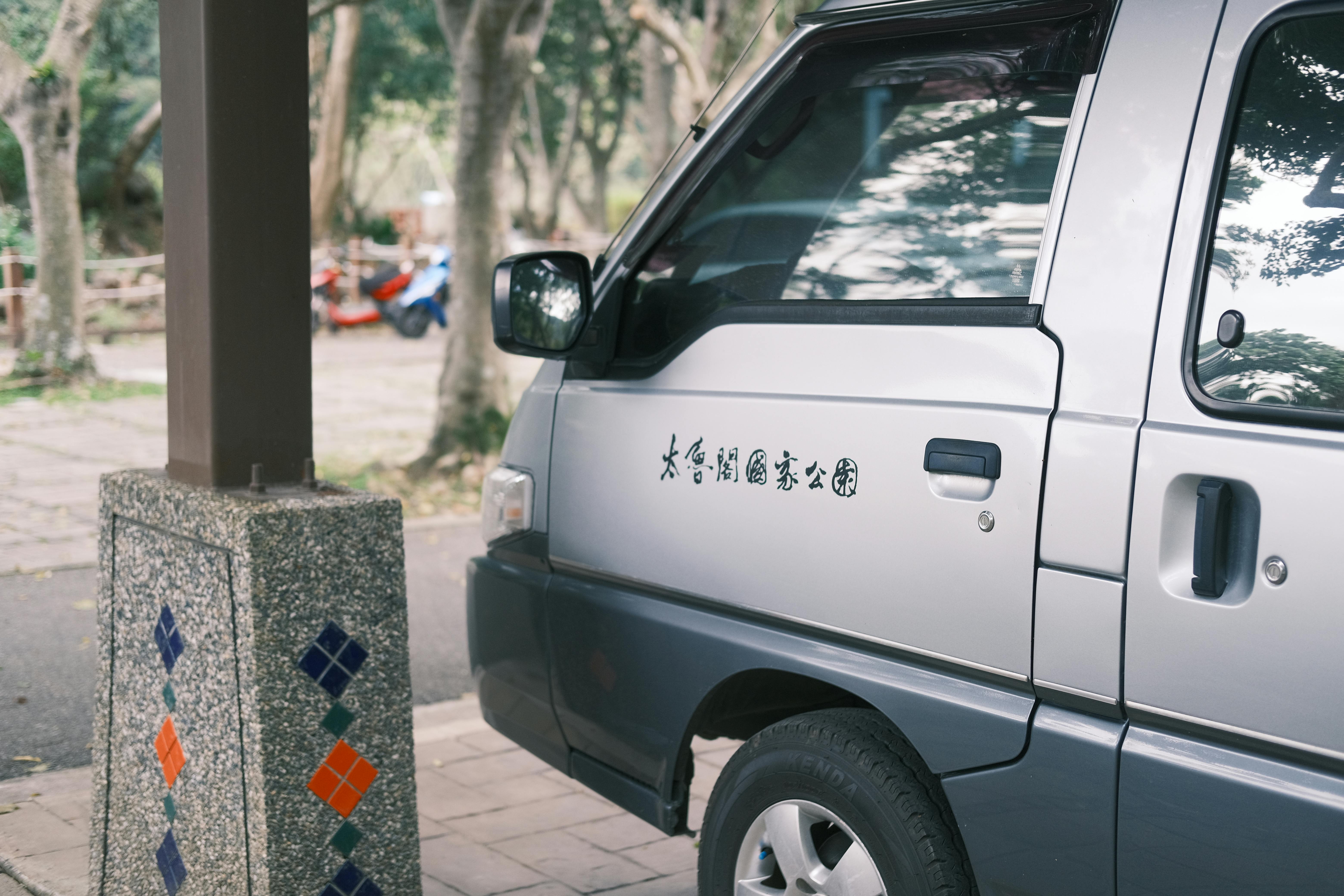 A silver minivan parked outdoors at Taroko National Park, featuring Asian script.