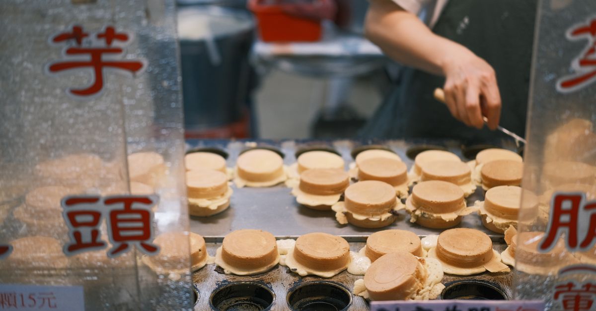 Captured at a bustling market, a street vendor prepares traditional Japanese dorayaki snacks with care.