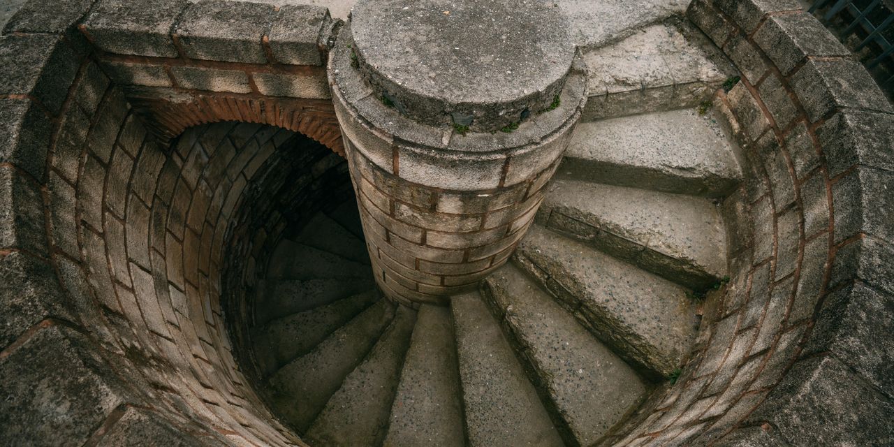 Top view of a spiraling stone staircase outdoors, showcasing architectural beauty.