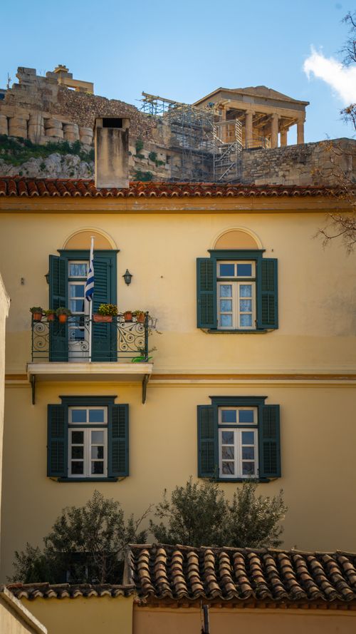 Free Yellow building façade with green shutters under the Acropolis in Athens, Greece. Stock Photo