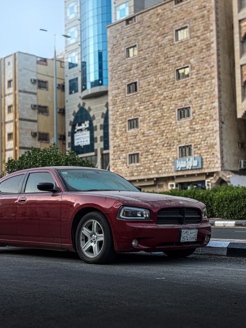 Free Modern red car parked on city street beside tall urban buildings, creating a realistic urban scene. Stock Photo