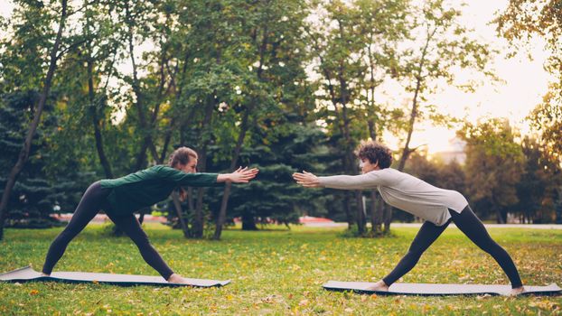 Two women engaging in outdoor yoga session amidst autumn trees.