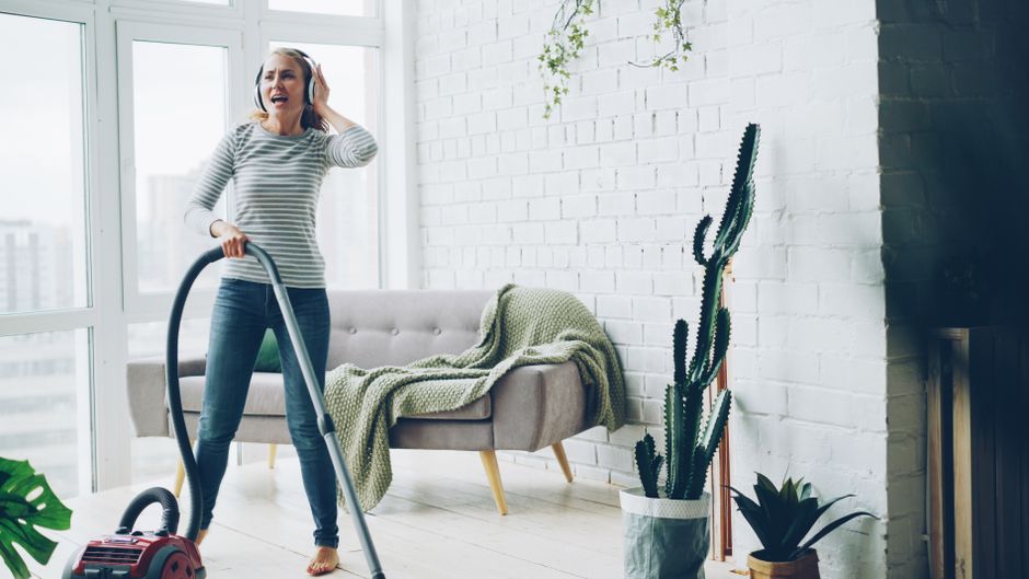 Best Robot Vacuums for Pet Hair in 2025: Ultimate Guide Cheerful woman vacuuming indoors while listening to music.