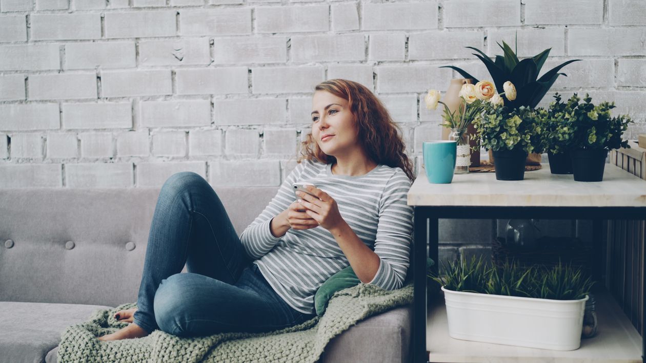 A woman enjoying a relaxing moment on a couch surrounded by plants