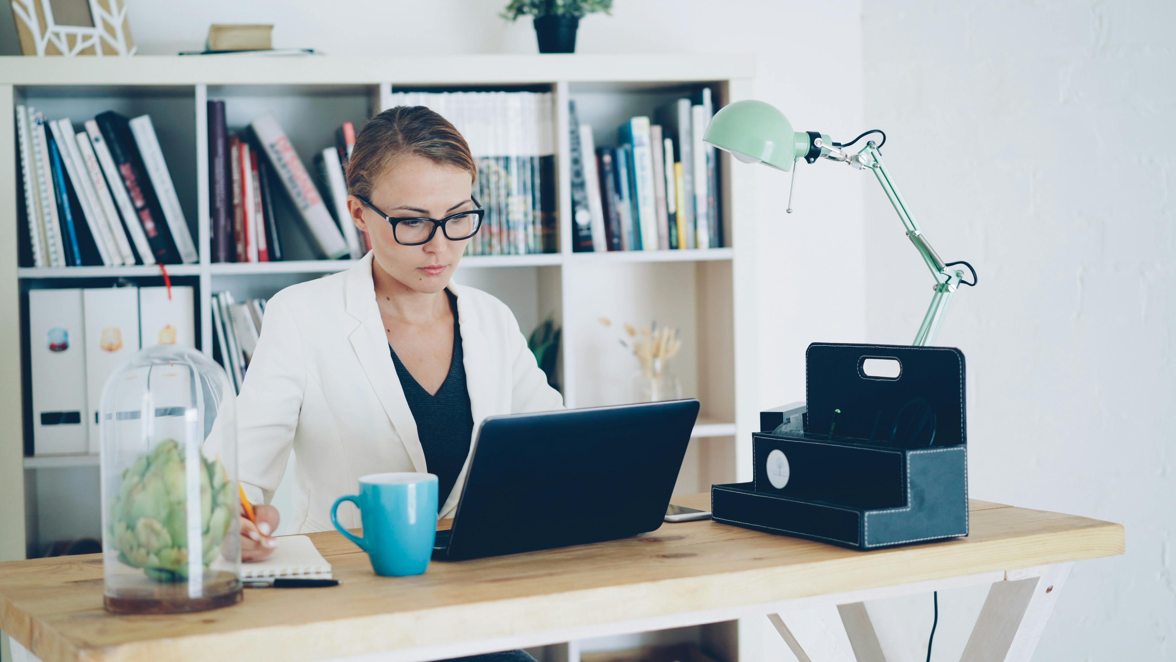 Businesswoman in office working on a laptop at a wooden desk.