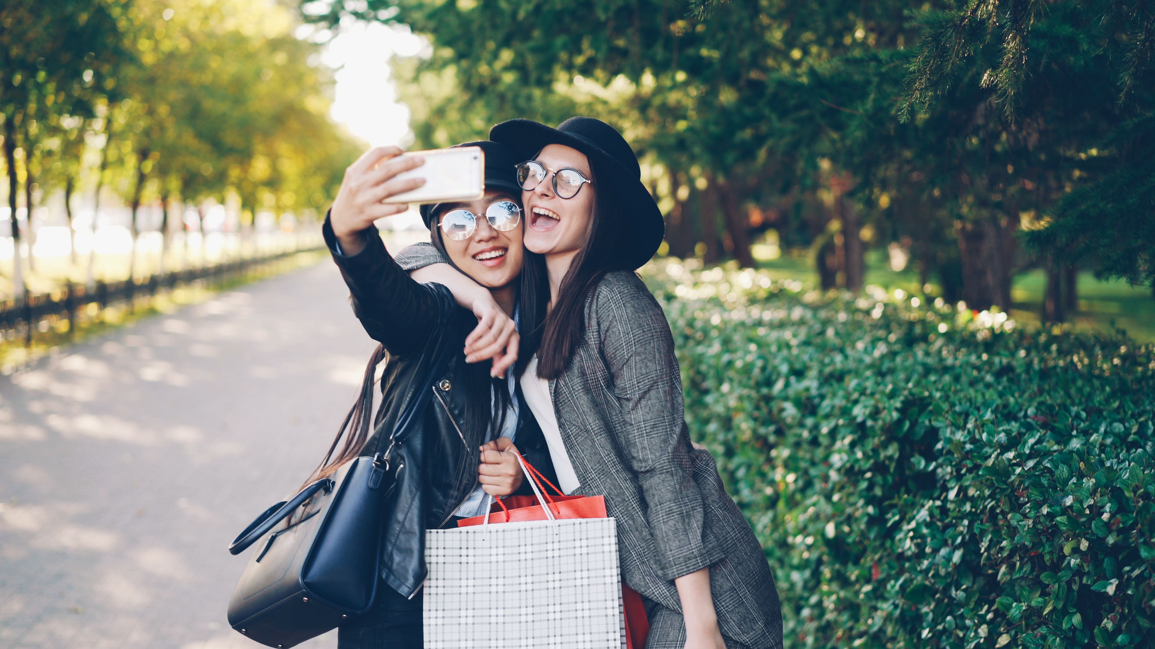 Two joyful women taking a selfie outdoors, enjoying a sunny day.