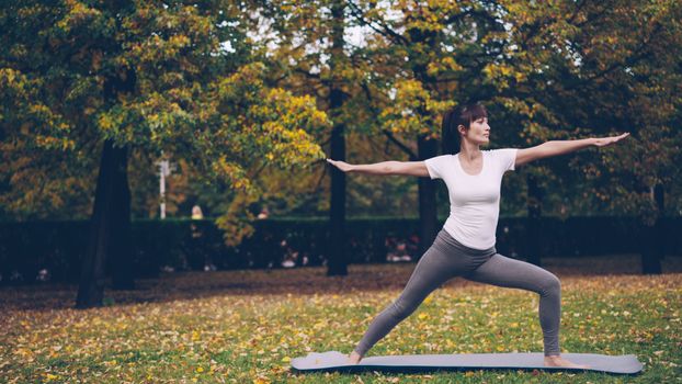 Woman performs yoga pose in a serene autumn park setting, embracing mindfulness and nature.