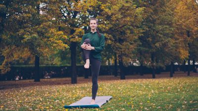 Standing Knee Cradle — outdoor yoga pose in an autumn park. Photo by Vitaly Gariev on Pexels