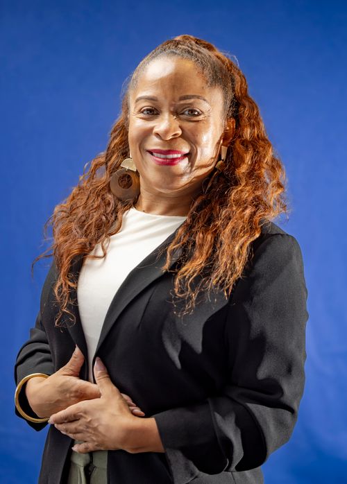 Free Smiling woman in business attire with blue backdrop, exuding confidence. Stock Photo