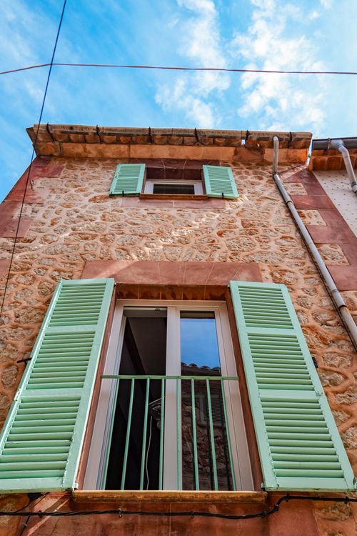 Free Rustic stone building with charming green shutters under a bright blue sky in Ibiza, Spain. Stock Photo