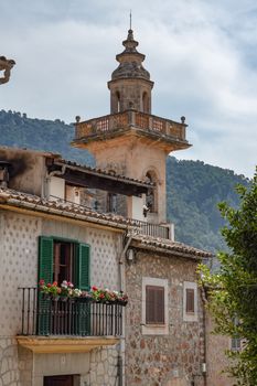 A quaint bell tower amidst Mediterranean architecture in a Spanish village setting.