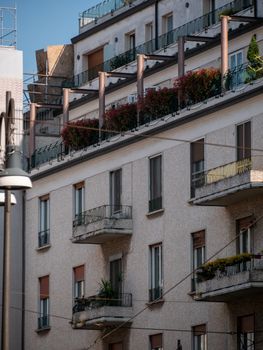 A street view of a residential building with balconies and plants, capturing urban architecture.