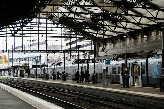 Train station in Paris, France, with people boarding trains. Urban transit scene.