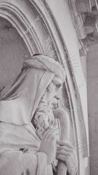 A detailed grayscale image of a historic stone statue with architectural elements in Malta.