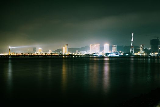 A stunning nighttime cityscape featuring illuminated buildings and a reflective waterfront, creating a serene urban atmosphere.