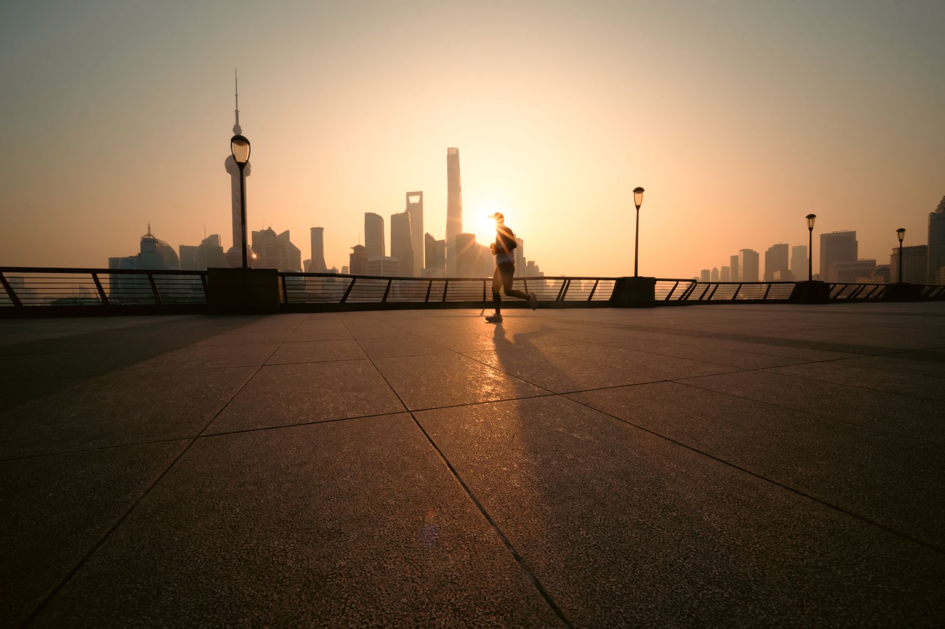 Dynamic image of a runner silhouetted against the sunrise and Shanghai skyline.