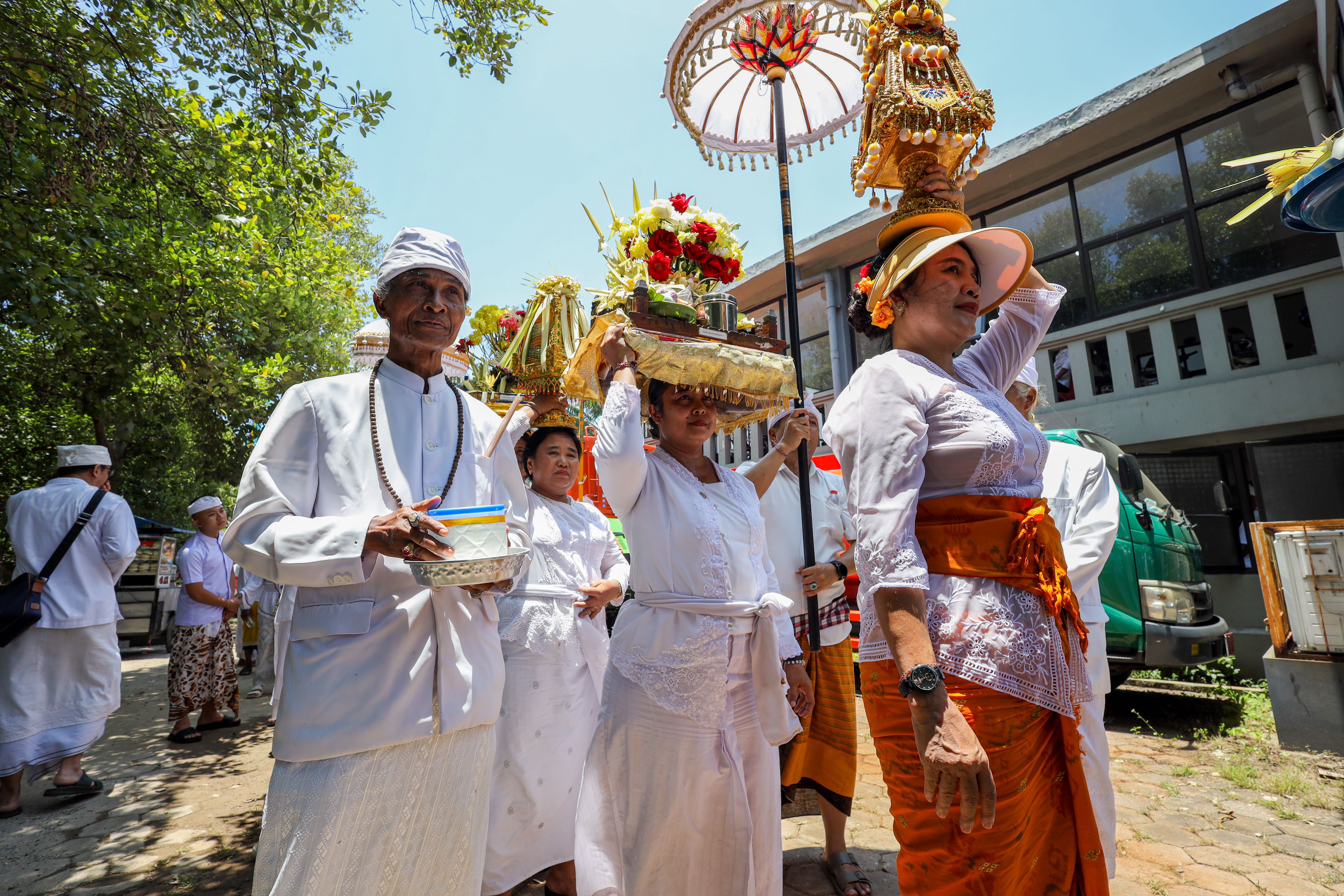 Balinese people in traditional attire participating in a vibrant Hindu ceremony outdoors.