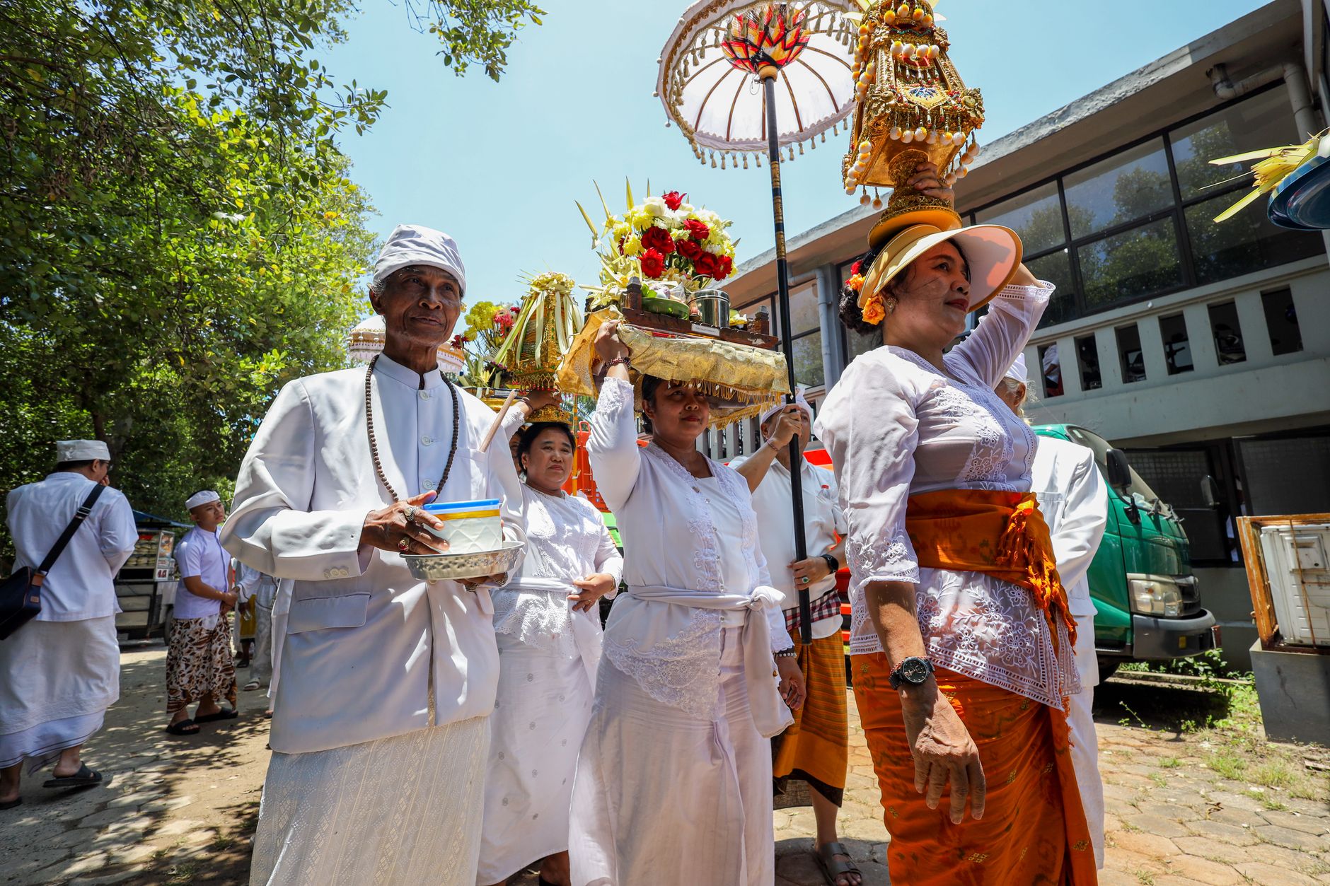 Balinese people in traditional attire participating in a vibrant Hindu ceremony outdoors.