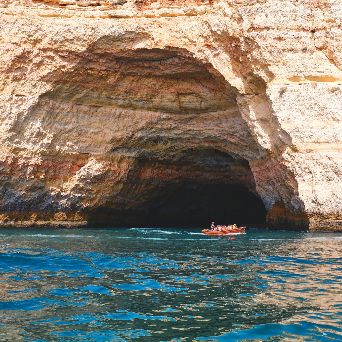 Golden Algarve cliffs and a sea cave over turquoise water