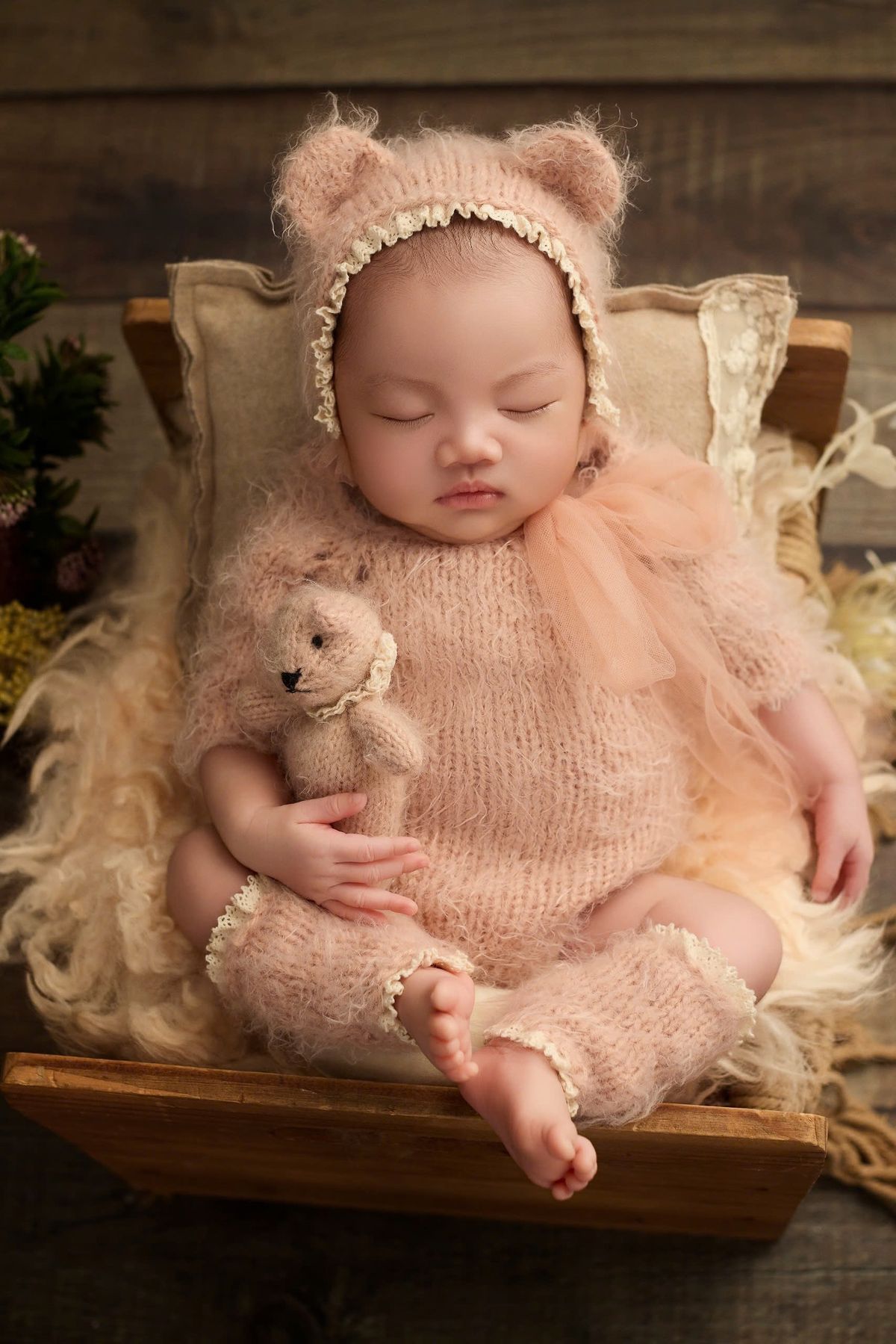 Baby sleeping peacefully holding a small teddy bear