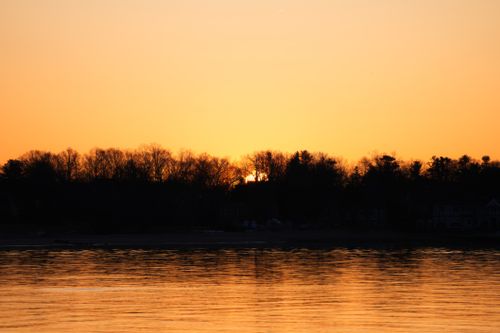 Free Captivating sunset view with trees reflecting on a calm lake surface. Stock Photo