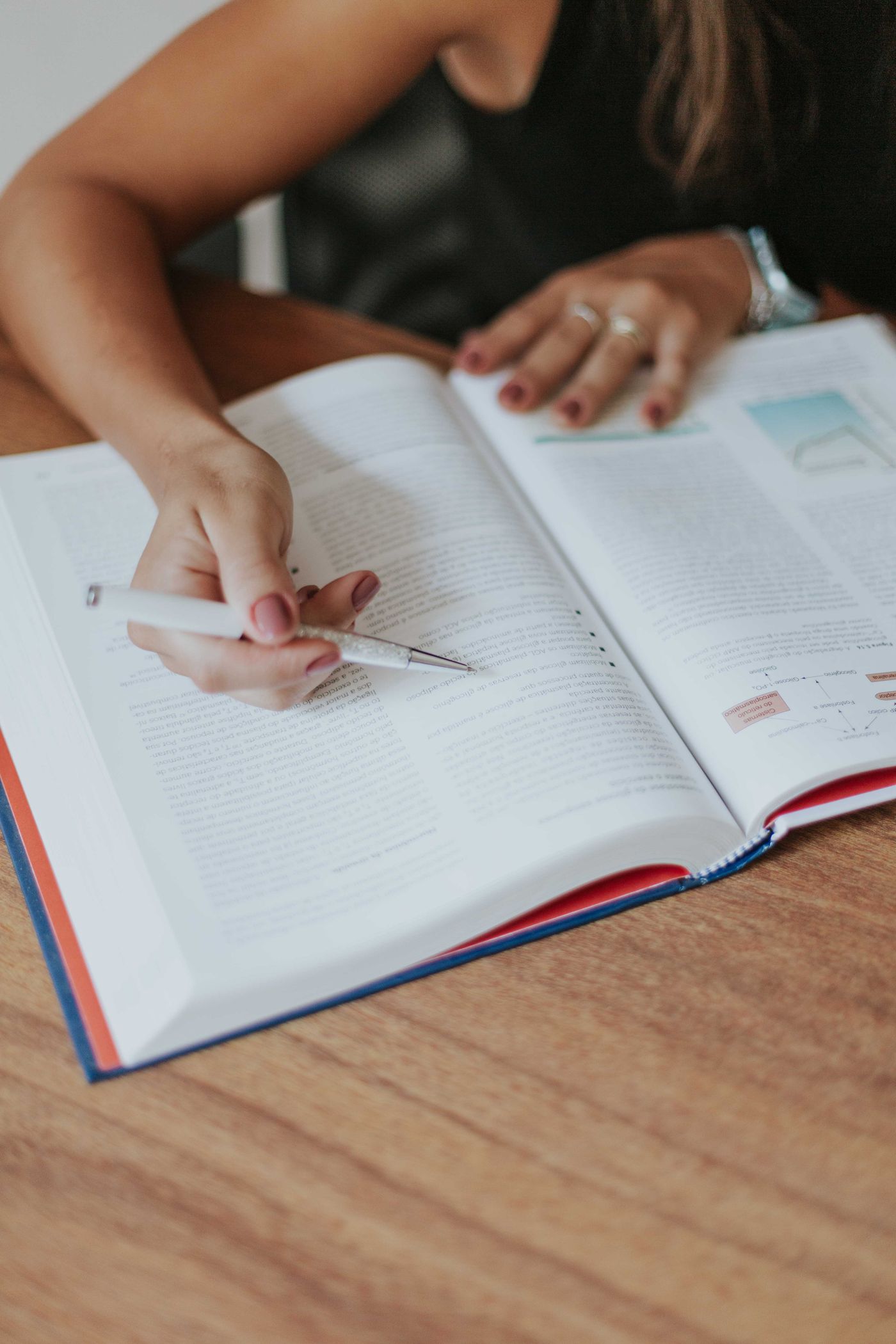 Reading a textbook at a wooden desk, pen in hand
