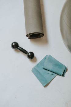 A flat lay of home workout essentials including a mat, dumbbell, and resistance band.