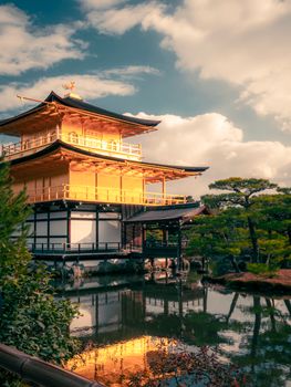 Kinkaku-Ji, the Golden Pavilion in Kyoto, beautifully reflected in a serene pond under a bright sky.