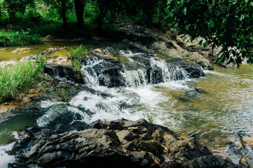 Free Serene waterfall flowing over rocks in the lush greenery of Kon Tum, Vietnam. Stock Photo
