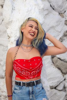 A joyful woman with colorful hair wearing a red bandana top. Casual outdoor fashion with a vibrant smile.