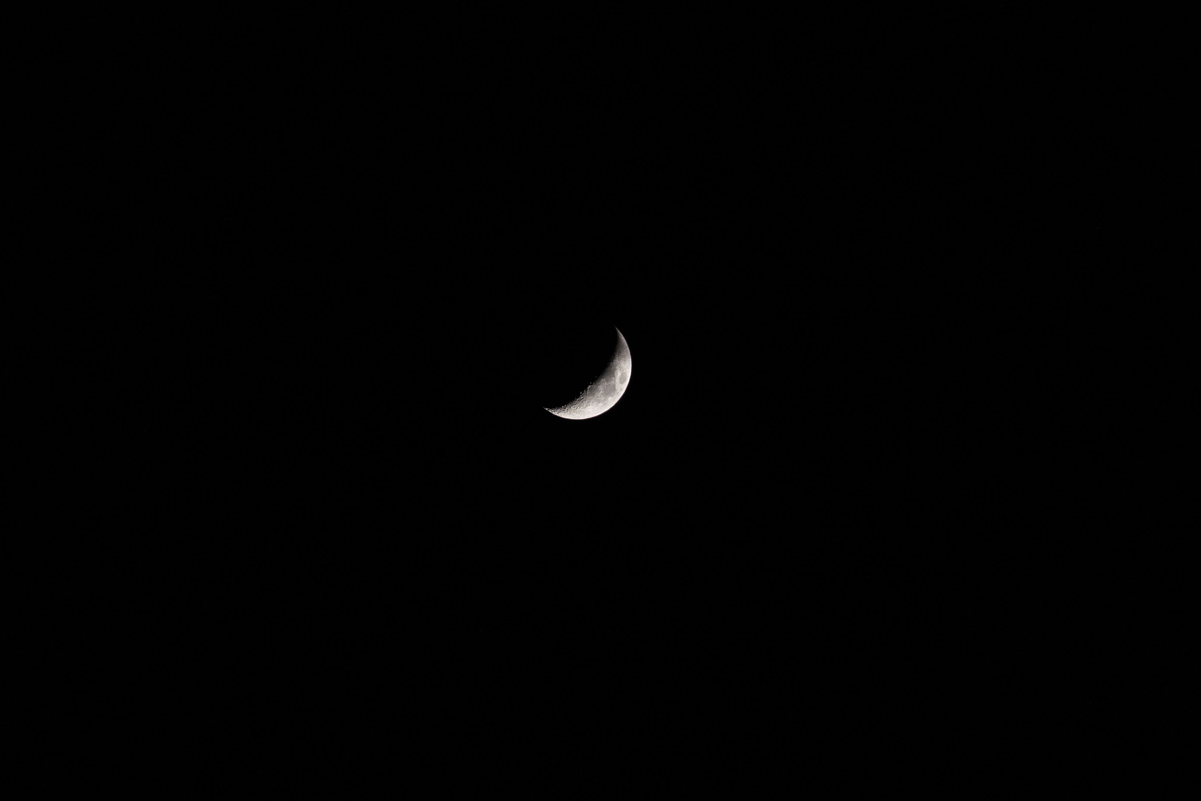 Minimalistic black and white image of the crescent moon against a dark night sky.