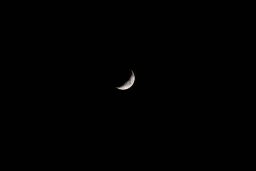 Minimalistic black and white image of the crescent moon against a dark night sky.