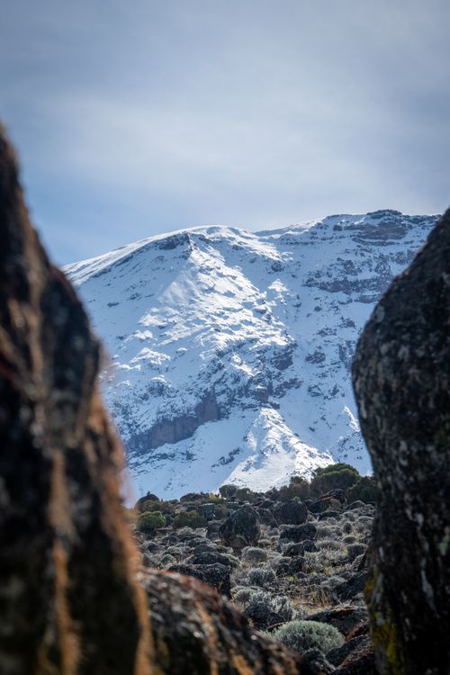 Free Majestic snow-covered mountain peak framed by rocky foreground. Stock Photo