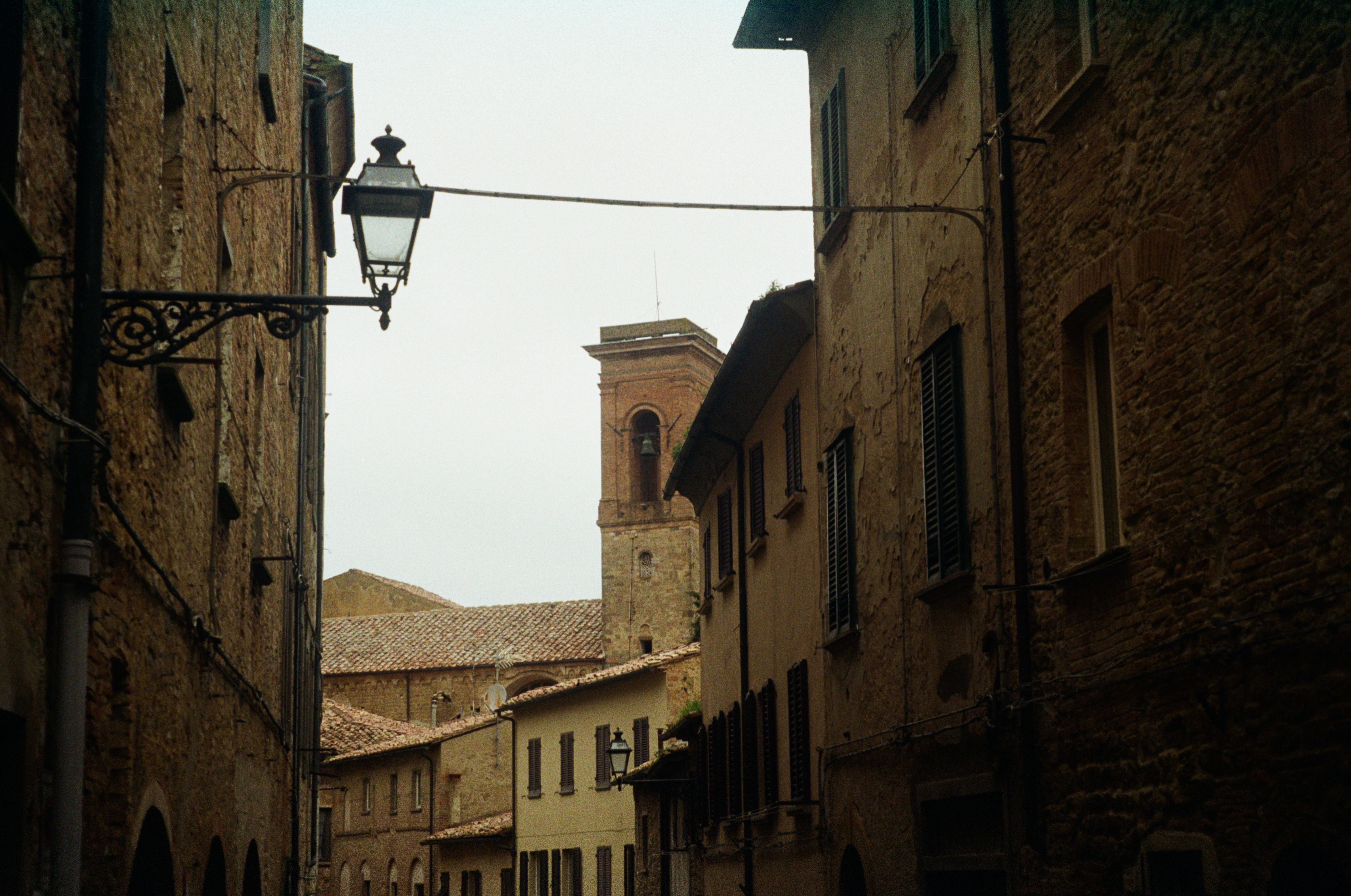 Charming narrow alley with vintage street lamp and rustic stone buildings.