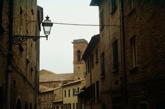 Charming narrow alley with vintage street lamp and rustic stone buildings.