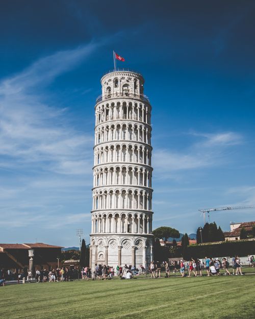 Free Iconic Leaning Tower of Pisa under clear blue sky with tourists in Italy. Stock Photo