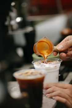 Close-up of espresso being poured into iced latte in a cafe setting.