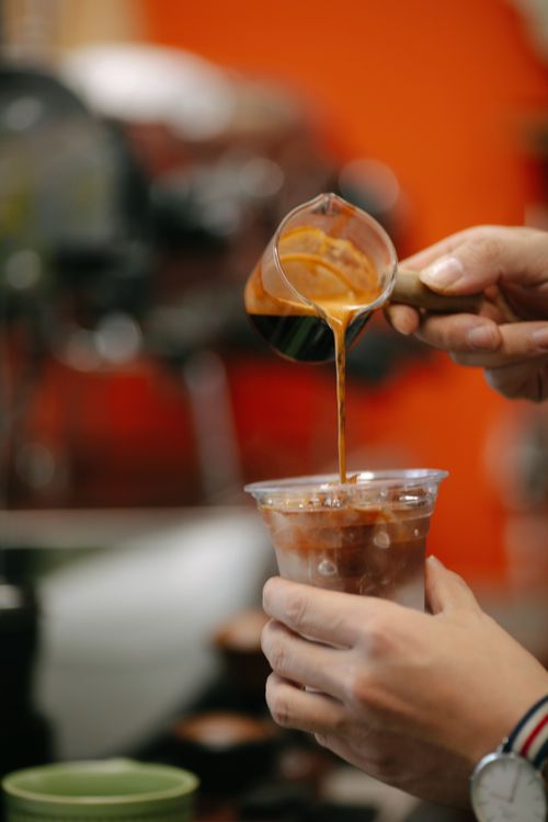 Free Close-up of barista pouring freshly brewed espresso into iced drink in coffee shop. Stock Photo