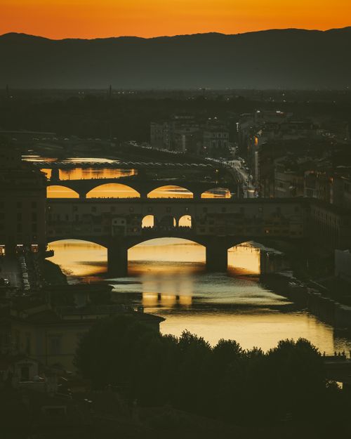Free Magical sunset view of Ponte Vecchio reflecting on Arno River in Florence. Stock Photo