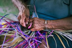 Close-up of senior hands skillfully weaving a colorful basket, highlighting traditional craftsmanship.