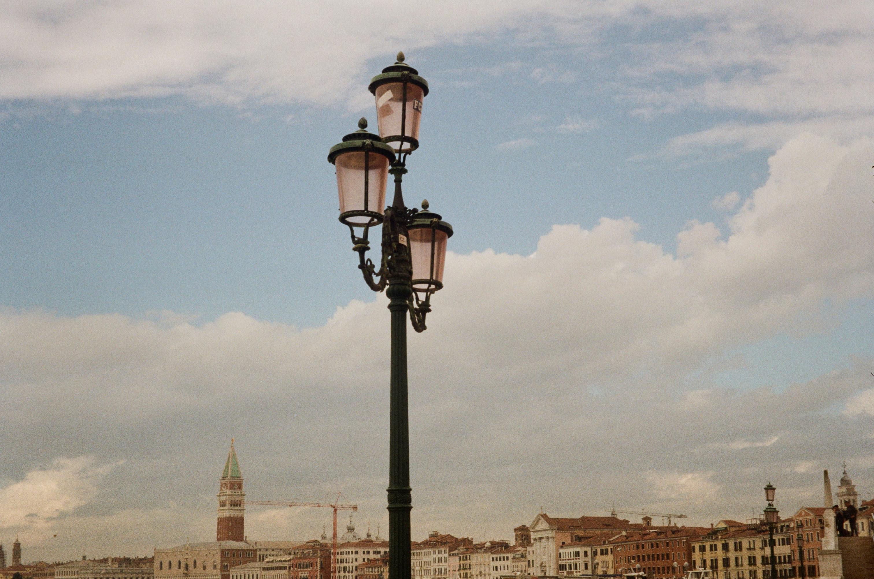A classic street lamp against the picturesque Venice skyline under a cloudy sky.
