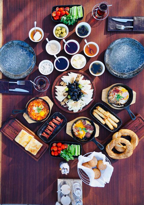 Free Flat lay of a rustic breakfast table with diverse dishes including eggs, pastries, and vegetables. Stock Photo