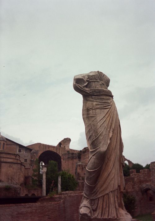 Free A captivating view of a headless Roman statue amid ancient ruins on a cloudy day. Stock Photo