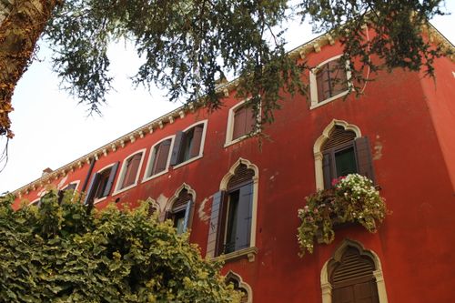 Free Explore the charm of Venetian architecture with a vibrant red facade adorned by flowers in Venezia, Italy. Stock Photo