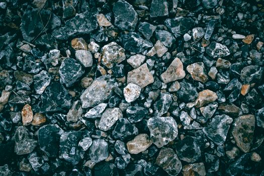 A detailed close-up of textured gravel featuring various stones and rocks outdoors.