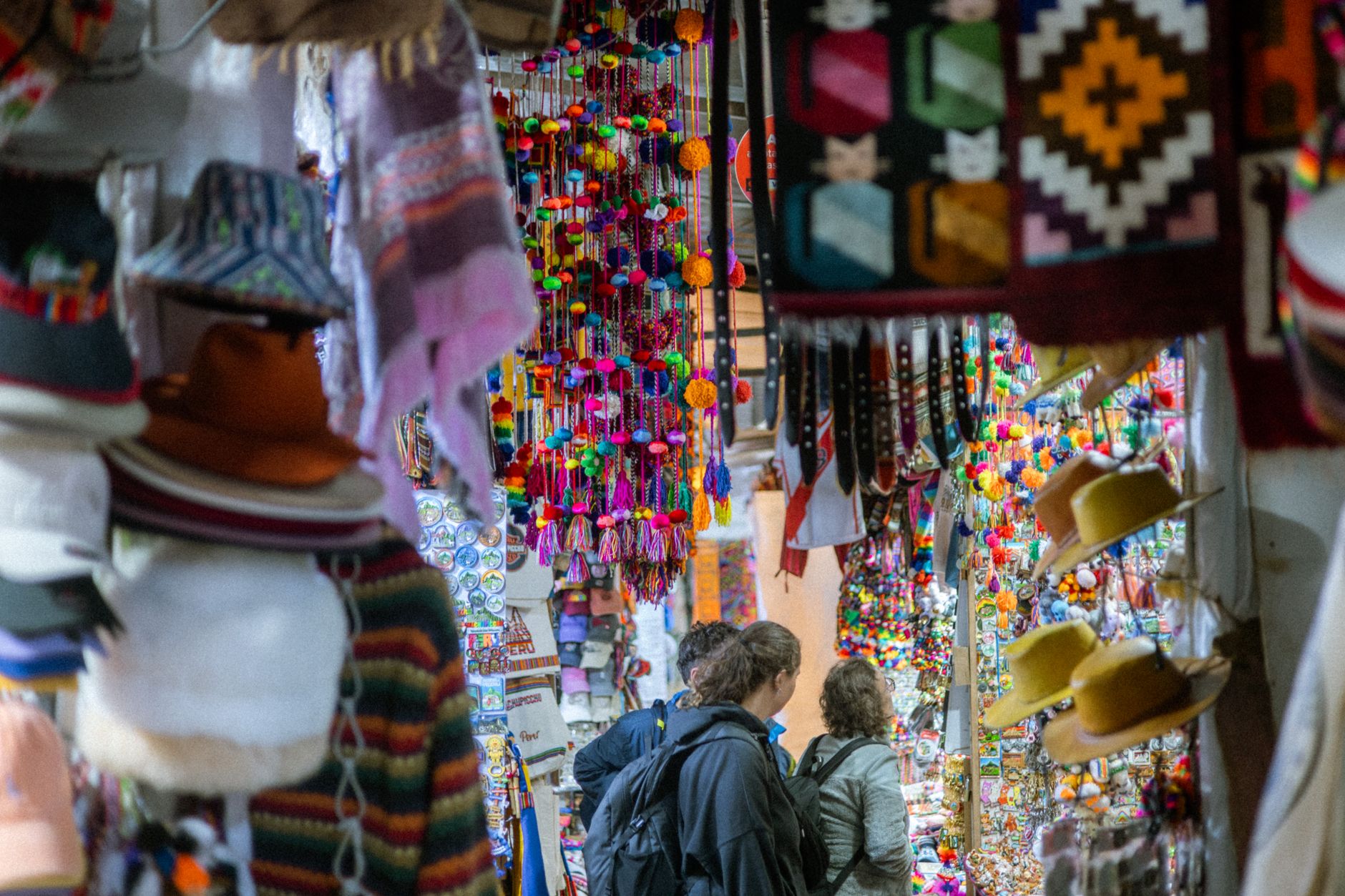 Vibrant handicrafts and tourists at a bustling market in Machu Picchu Pueblo, Cusco, Peru.