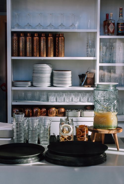 Free Elegant bar counter setup with glassware, decorative bottles, and a citrus juicer in a modern setting. Stock Photo