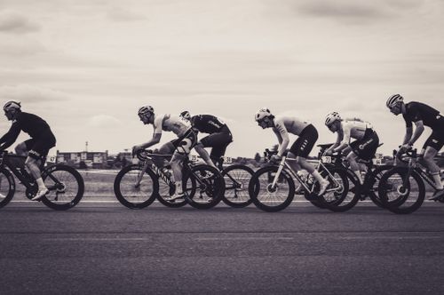 Free Monochrome photograph of a fast-paced road cycling race with multiple cyclists in action. Stock Photo