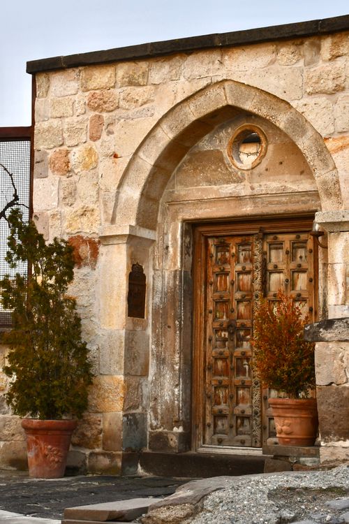 Free Historic stone building with an arched wooden door and potted plants. Stock Photo